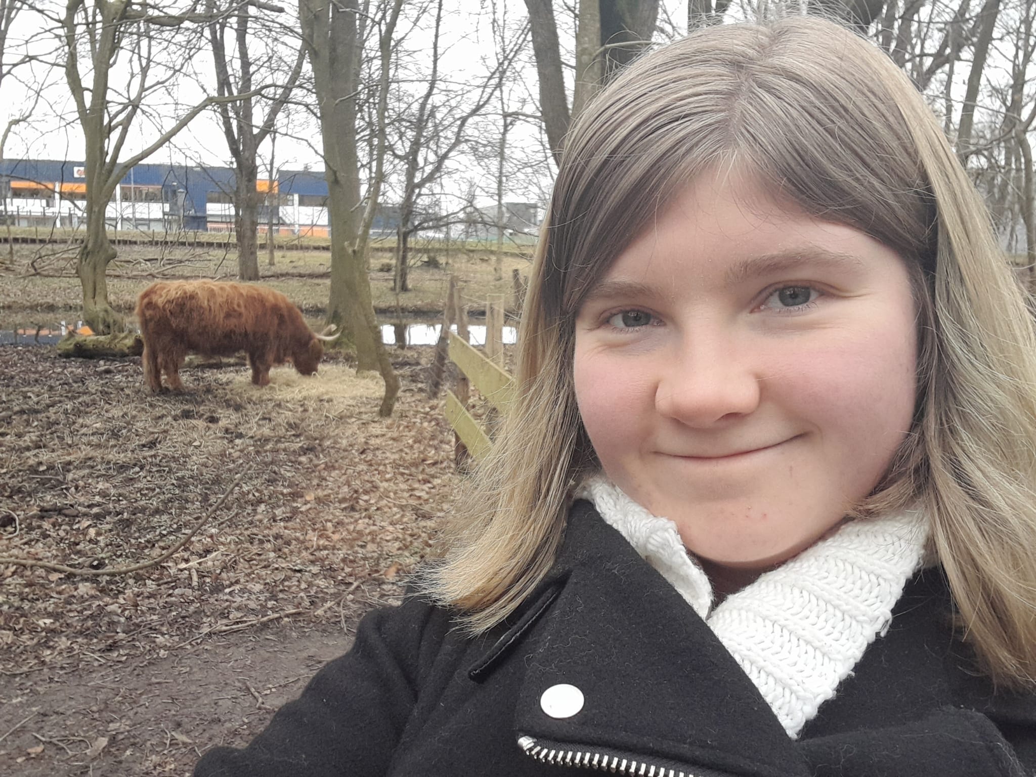 Photo of me with a higland cattle in the background in the winter